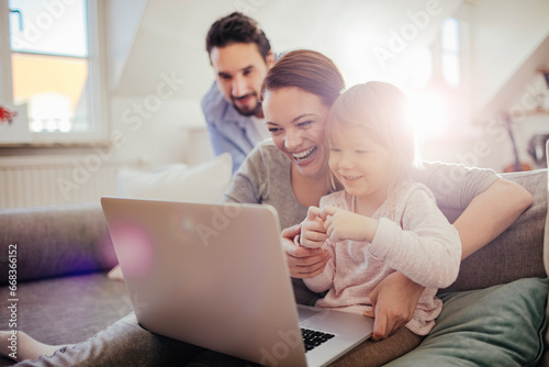 Young family looking at laptop on the couch at home