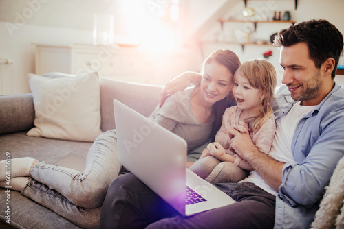 Young family looking at laptop on the couch at home © Geber86