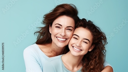 Affectionate loving middle-aged Caucasian mother hugs her adult child daughter on a blue background and looks at the camera. beautiful senior mother and her adult daughter hugging and smiling photo