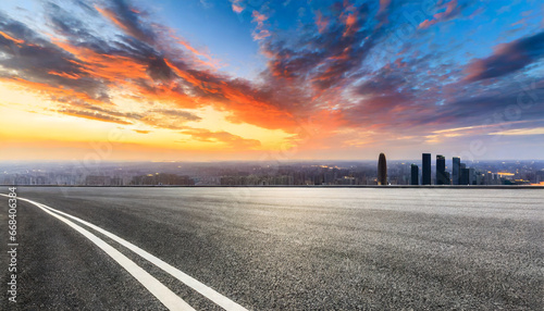 asphalt road and city skyline with colorful sky clouds at sunset photo