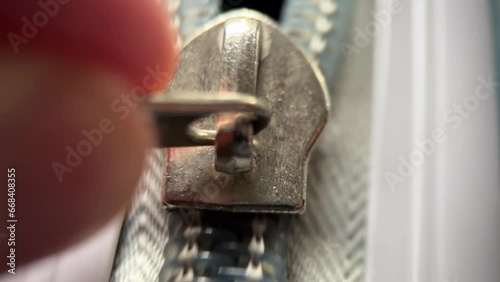 Man's hand opens the zipper of a grey polycarbonate travel suitcase. Extreme close-up