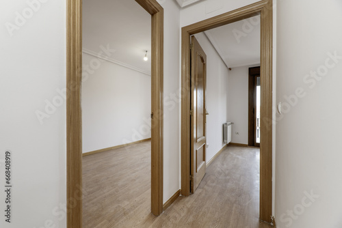 Hallway distributor of residence housing with oak wood carpentry on doors and moldings and light-colored flooring on the floor
