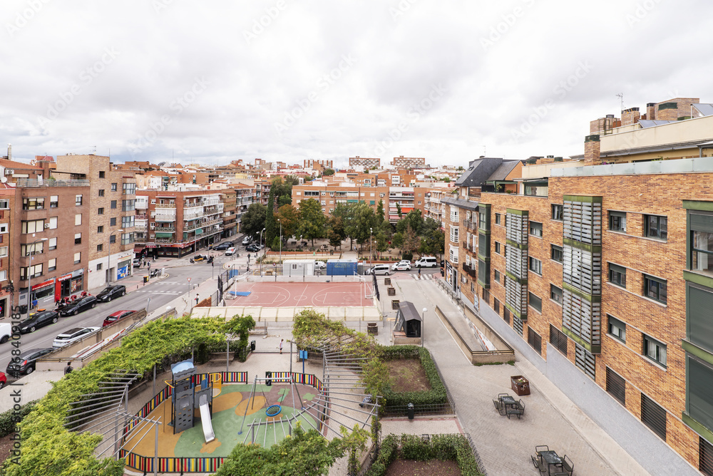 Panoramic image of an open block between streets with facades and roofs of urban residential buildings and a playground