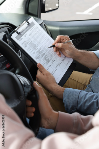 Driving school. Student passing driving test with examiner in car, closeup