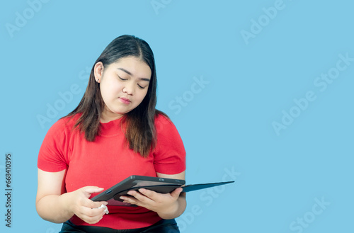 Portrait business girl young woman asian chubby fat cute beautiful pretty one person wearing red shirt in office holding digital tablet and smiling standing with copy space on isolated blue blackgrond photo