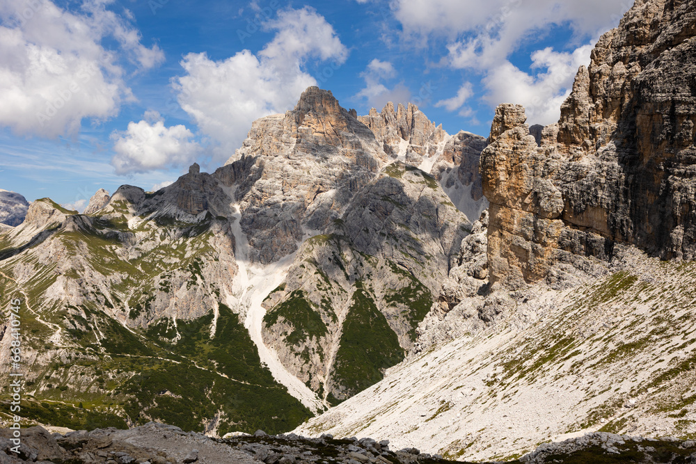 Bright rocks and mountain peaks are illuminated by bright daytime summer sun in Dolomites.