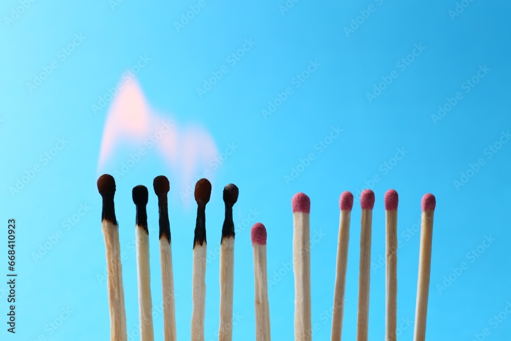 Burning and whole matches on light blue background. Space for text Burning and whole matches on light blue background. Space for text