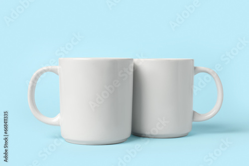 Two white ceramic mugs on light blue background