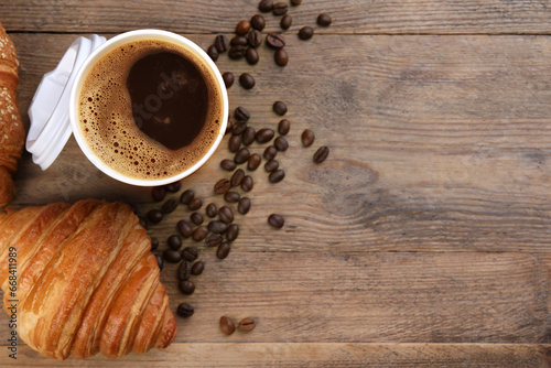 Coffee to go. Paper cup of tasty drink  croissants and beans on wooden table  flat lay with space for text