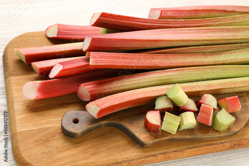 Many cut rhubarb stalks on white wooden table, closeup