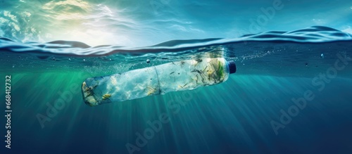 Floating plastic bottle pollutes the blue sea water and the environment photo