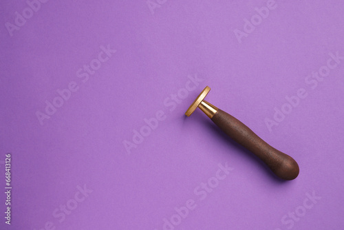 One stamp tool with wooden handle on purple background, top view. Space for text