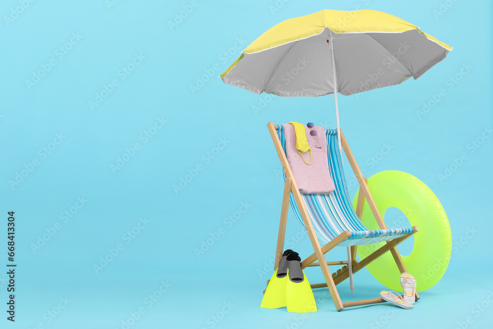 Deck chair, umbrella and beach accessories against light blue background, space for text. Summer vacation Deck chair, umbrella and beach accessories against light blue background, space for text. Summer vacation