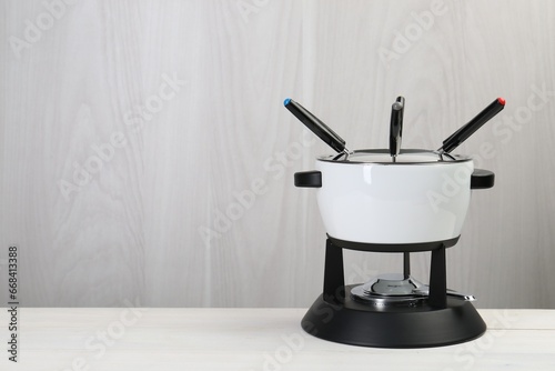 Fondue set on white wooden table, space for text