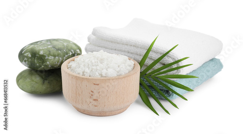Bowl of sea salt, towels, massage stones and palm leaf isolated on white. Spa treatment