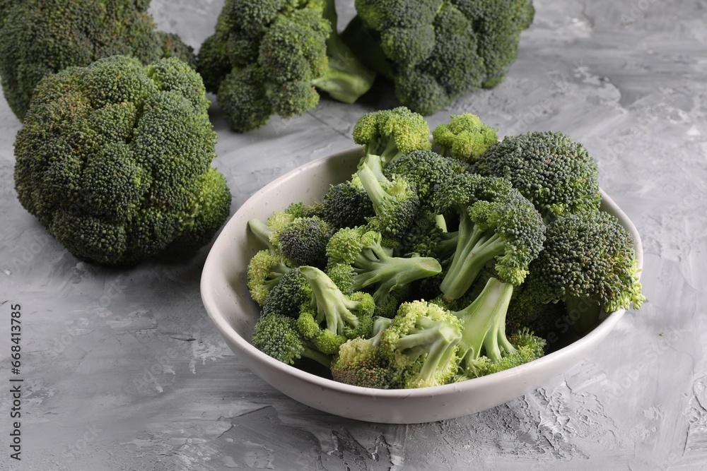 Bowl of fresh raw broccoli on grey textured table Bowl of fresh raw broccoli on grey textured table