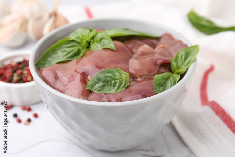 Bowl with raw chicken liver and basil on white textured table, closeup Bowl with raw chicken liver and basil on white textured table, closeup