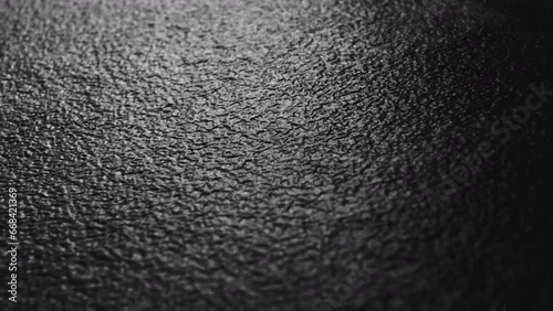 Close-up of a DARK TEXTURED surface illuminated by side light. Macro dolly movement creates abstract visual background.