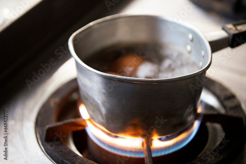 Stainless steel pot with boiling water on the gas stove.