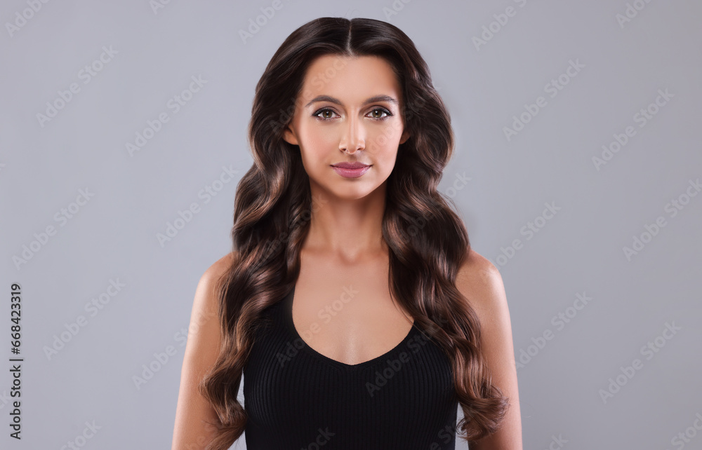 Gorgeous woman with shiny wavy hair on grey background. Professional hairstyling Gorgeous woman with shiny wavy hair on grey background. Professional hairstyling