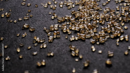 Macro dolly shot of BROWN SUGAR crystals scattered on a dark background. Detailed view highlights the texture and natural golden color.
