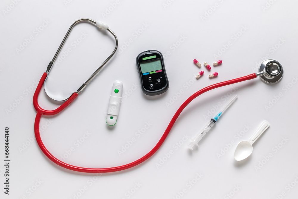 Glucose meter, stethoscope, syringe and pills on a white background. The concept of getting rid of diseases. Glucose meter, stethoscope, syringe and pills on a white background. The concept of getting rid of diseases.