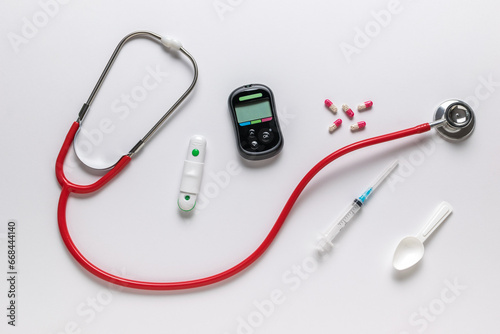 Glucose meter, stethoscope, syringe and pills on a white background. The concept of getting rid of diseases.