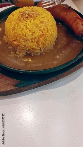 Overhead view of a foodie tourist eating turmeric rice and Hungarian sausage or disznotoros served on a sizzling hot plate photo