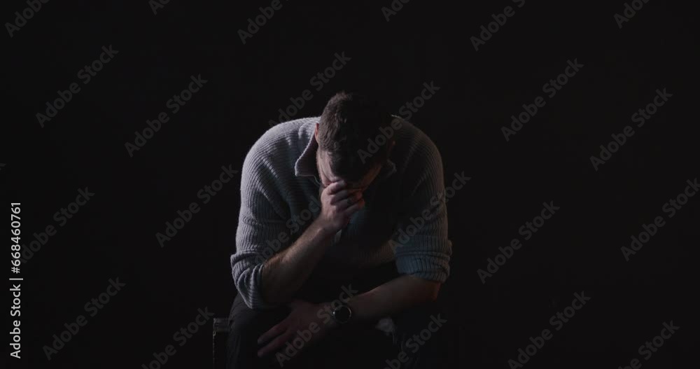 Sitting, sad man sobs in dark room, black background. Static Sitting, sad man sobs in dark room, black background. Static