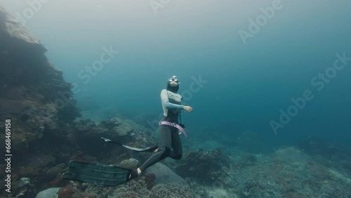 Freediving on a reef. Woman freediver swimming underwater along the reef in the sea photo