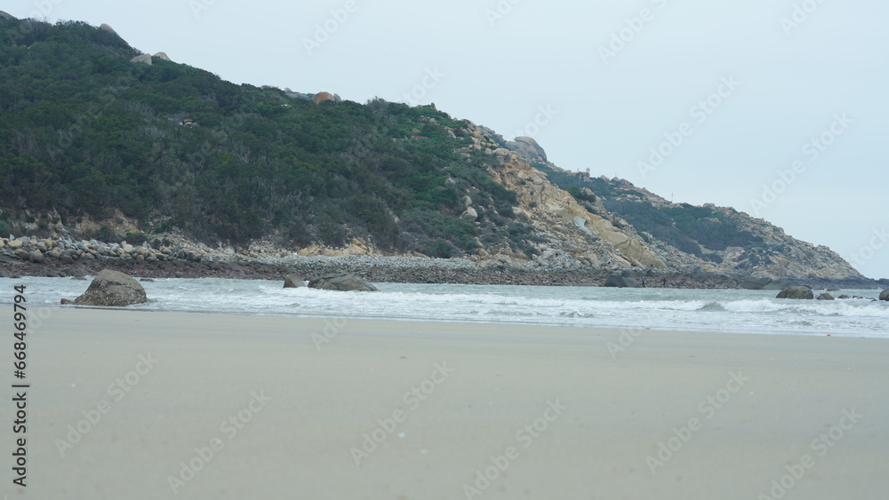 The ocean beach view with the rock shore and tide waves