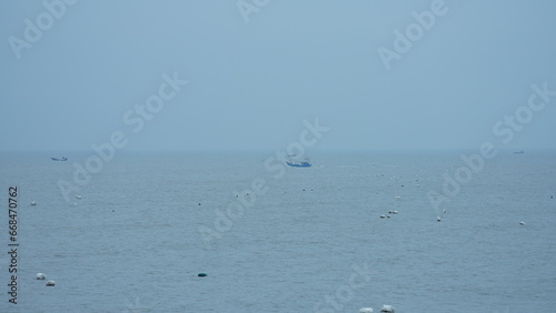The peaceful sea view with the fishing boat sailing on it in the cloudy day