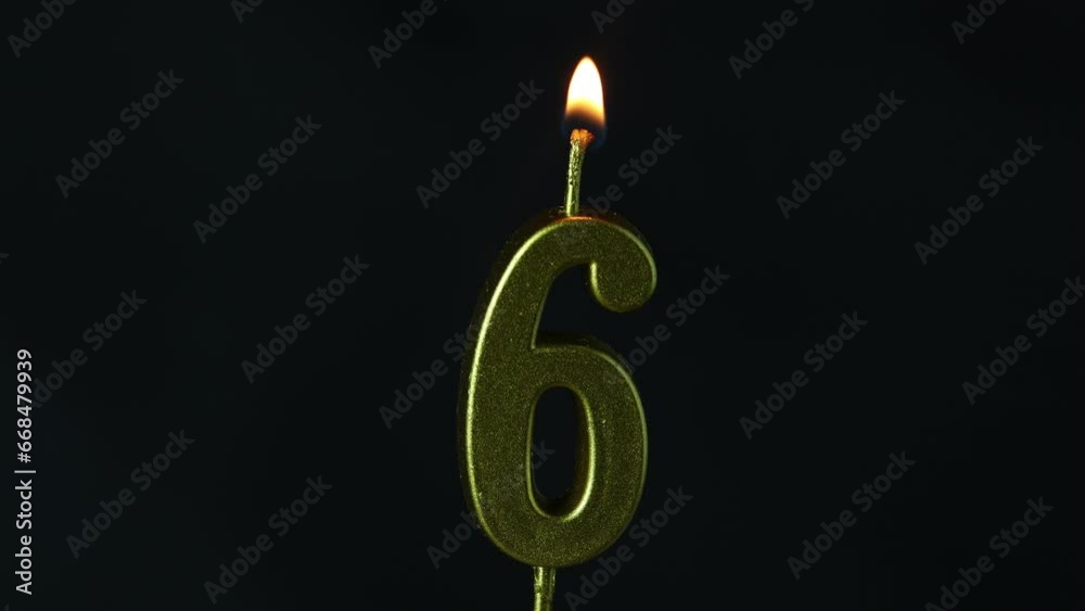 close up on the gold number six candle on a dark background.
close up on the gold number six candle on a dark background.