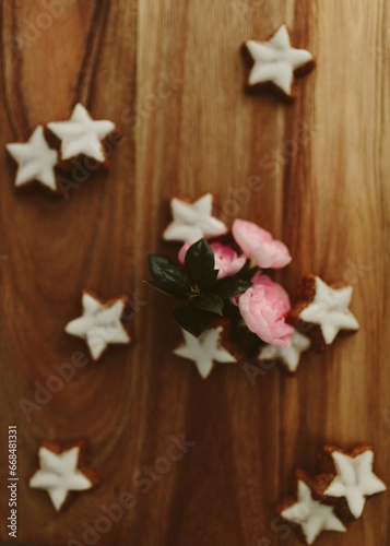 Gingerbread cookies in the shape of stars and pink roses on a wooden table. Christmas background. Winter card. Delicious pastries