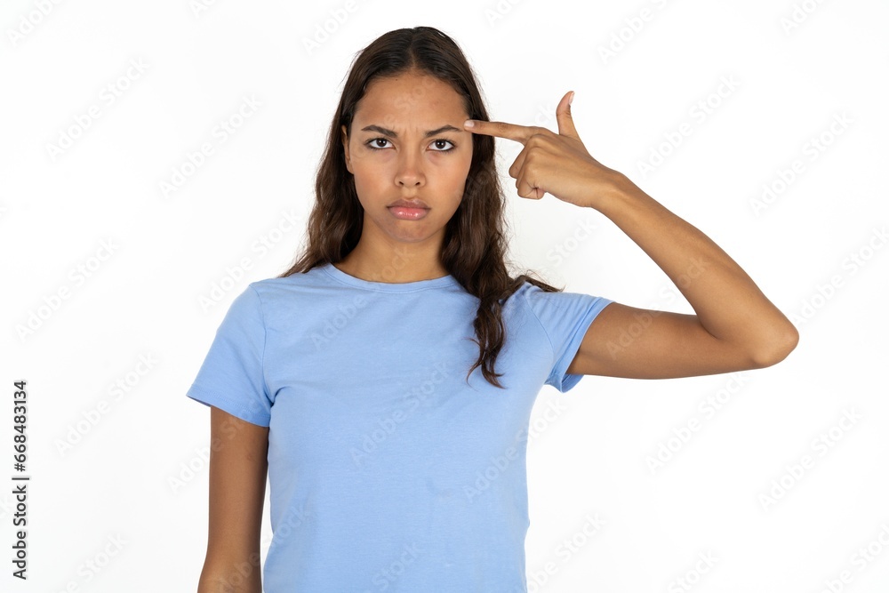 Unhappy Beautiful girl wearing blue T-shirt makes suicide gesture and imitates gun with hand, curves lips keeps two fingers on temple, shoots, being tired of everything, Unhappy Beautiful girl wearing blue T-shirt makes suicide gesture and imitates gun with hand, curves lips keeps two fingers on temple, shoots, being tired of everything,