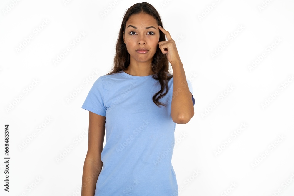 Beautiful girl wearing blue T-shirt tries to memorize something, keeps fore finger on temple, reminds information for exam, Beautiful girl wearing blue T-shirt tries to memorize something, keeps fore finger on temple, reminds information for exam,