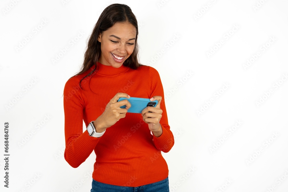 Beautiful girl wearing red sweater holding in hands cell playing video games or chatting Beautiful girl wearing red sweater holding in hands cell playing video games or chatting