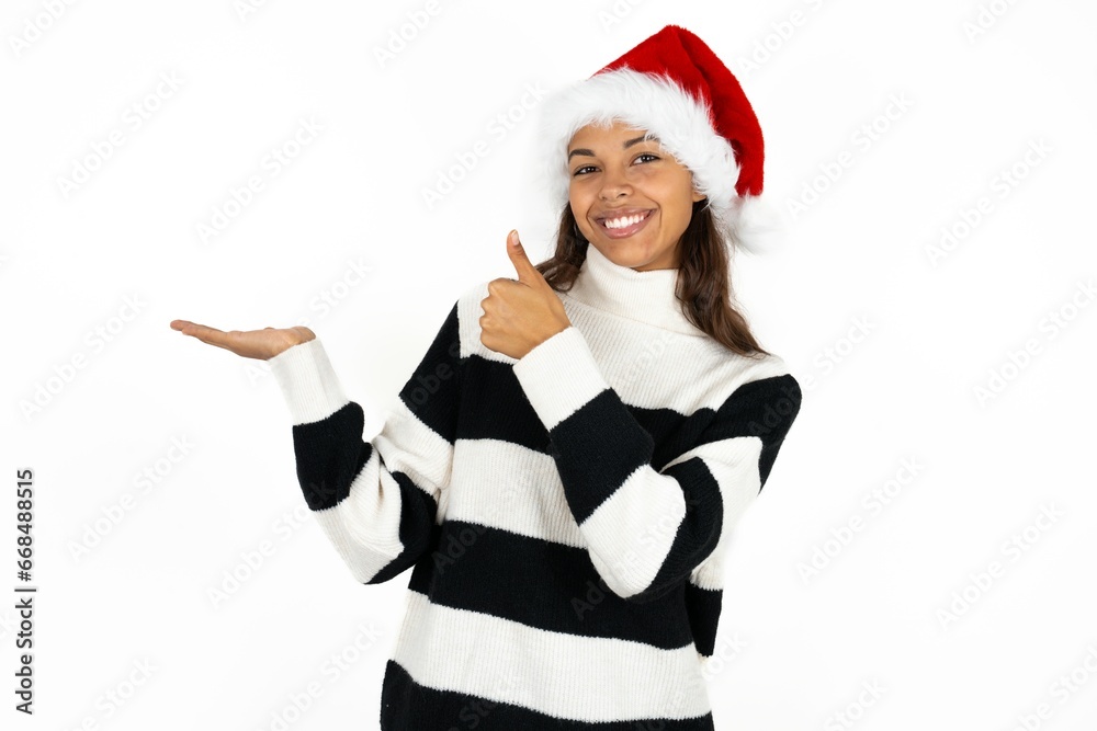Beautiful woman wearing christmas hat Showing palm hand and doing ok gesture with thumbs up, smiling happy and cheerful. Beautiful woman wearing christmas hat Showing palm hand and doing ok gesture with thumbs up, smiling happy and cheerful.