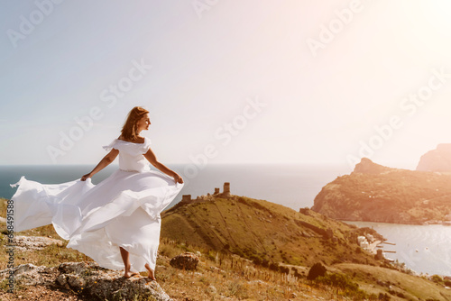 Wallpaper Mural Happy woman in a white dress and hat stands on a rocky cliff above the sea, with the beautiful silhouette of hills in thick fog in the background. Torontodigital.ca