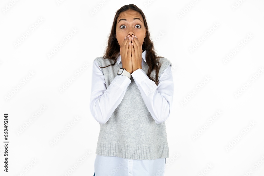 Young beautiful woman keeps hands on mouth, looks with eyes full of disbelief, being puzzled with amount of work Young beautiful woman keeps hands on mouth, looks with eyes full of disbelief, being puzzled with amount of work