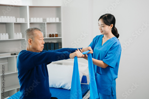 Asian physiotherapist helping elderly man patient stretching arm during exercise correct with dumbbell in hand during training hand with patient Back problems