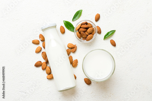 Tableau sur toile Top view of the almond milk in the glass bottle with almond nuts on the colored table
