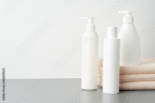 Set of blank cosmetic bottles and towels on gray background © fotofabrika