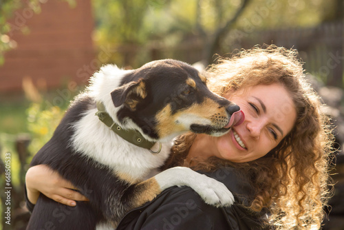A dog licks a woman's face outdoor.