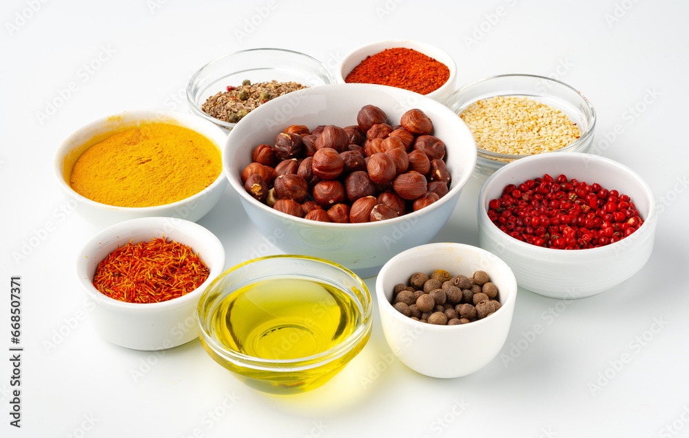 Bowls with spices and cooking ingredients on white background