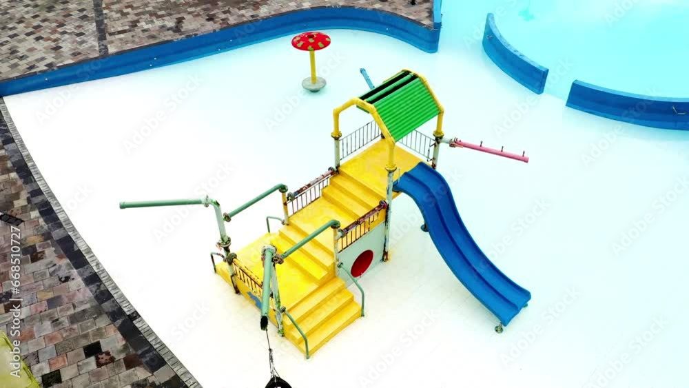 Close up of a slide for small children that is located at the side of a little playing house inside a swimming pool Close up of a slide for small children that is located at the side of a little playing house inside a swimming pool