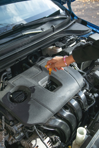 Woman checks the oil level in the car.