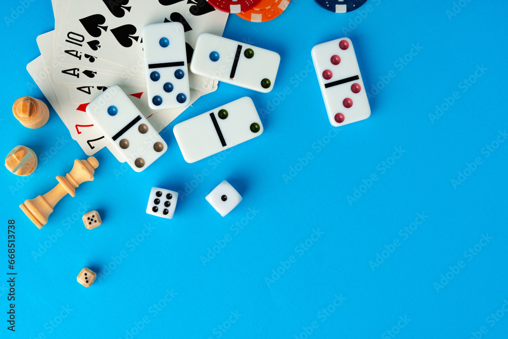 Items for playing chess, poker and domino on blue background studio shot Items for playing chess, poker and domino on blue background studio shot