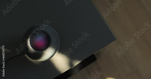 HomePod Mini speaker - the smart speaker is reacting to voice listening to human commands on the bedside table in the bedroom. Concept of a smart home. photo