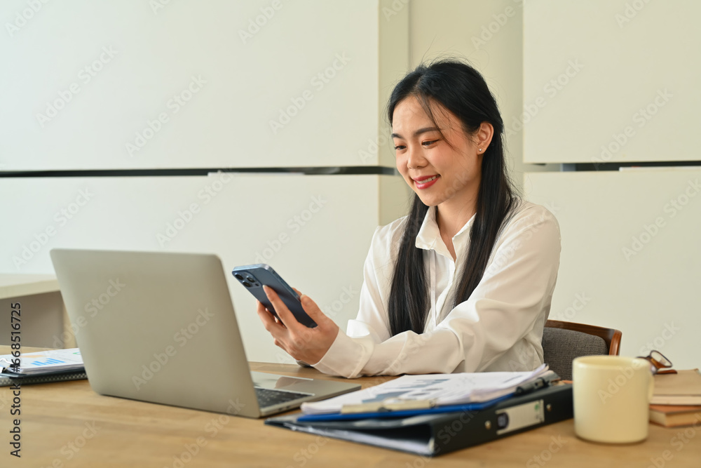 Beautiful businesswoman taking a break from work and using mobile phone at office desk Beautiful businesswoman taking a break from work and using mobile phone at office desk